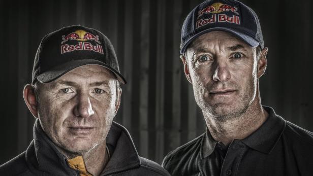 Zwei Männer mit Red Bull-Kappen blicken in die Kamera.
