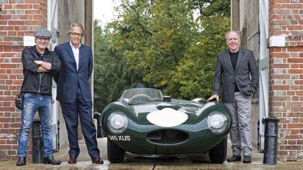 Drei Männer posieren vor einem grünen Jaguar D-Type Oldtimer.