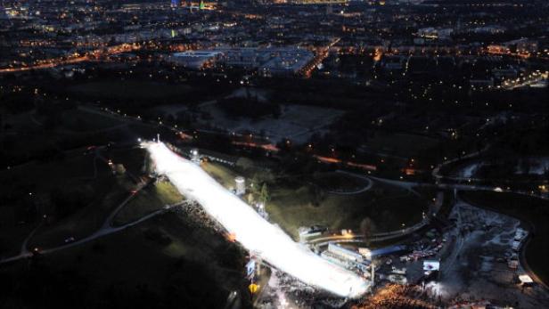 Luftaufnahme einer beleuchteten Skipiste in München bei Nacht.