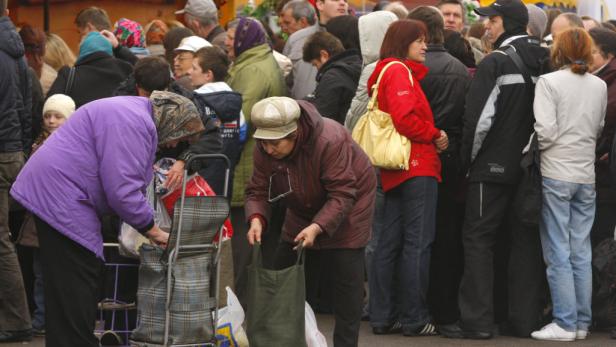Eine Menschenmenge steht an einem Marktstand an, um einzukaufen.
