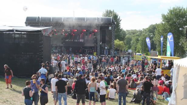 Eine Menschenmenge versammelt sich vor einer Bühne bei einem Open-Air-Konzert.