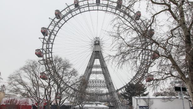 Das Wiener Riesenrad im Winter mit schneebedecktem Boden und kahlen Bäumen.