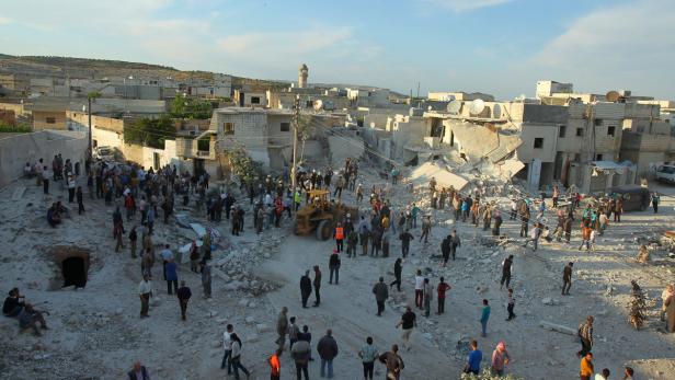 Nach einem Bombenangriff versammeln sich Menschen in einer zerstörten Stadt.