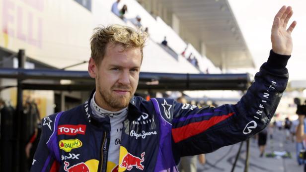 Sebastian Vettel winkt in seiner Rennfahrerjacke.