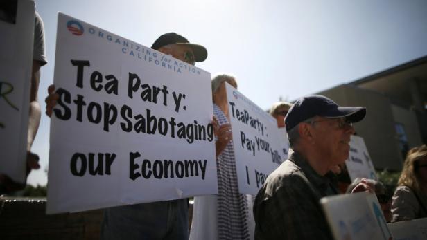 Menschen demonstrieren mit Schildern gegen die Tea Party.