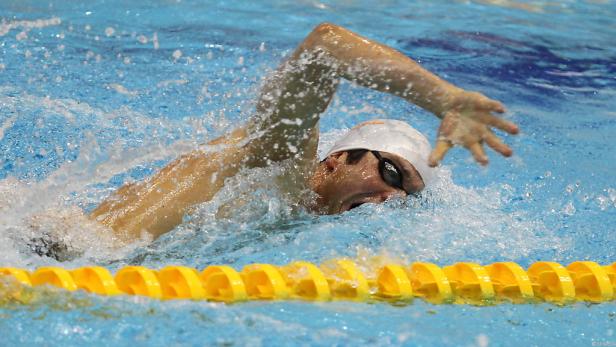 Ein Schwimmer mit Badekappe und Schwimmbrille im Schwimmbecken.