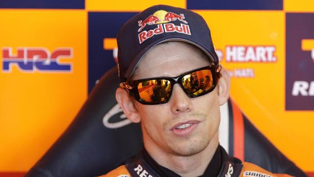 Ein Mann mit Sonnenbrille und Red Bull-Kappe vor einem orangefarbenen Hintergrund mit Logos.