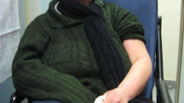 Eine Frau sitzt mit Tränen in den Augen auf einem blauen Stuhl.