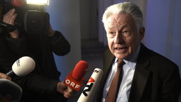 Ein Mann mit grauem Haar spricht in mehrere Mikrofone.