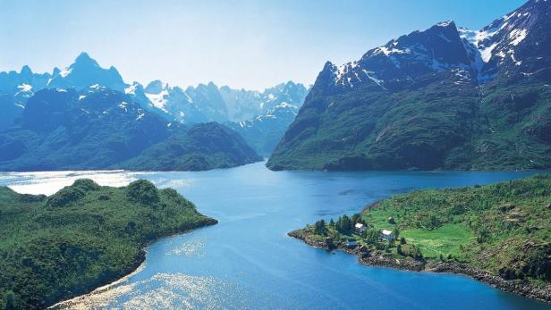 Eine blaue Wasserstraße schlängelt sich durch eine grüne Landschaft mit schneebedeckten Bergen im Hintergrund.