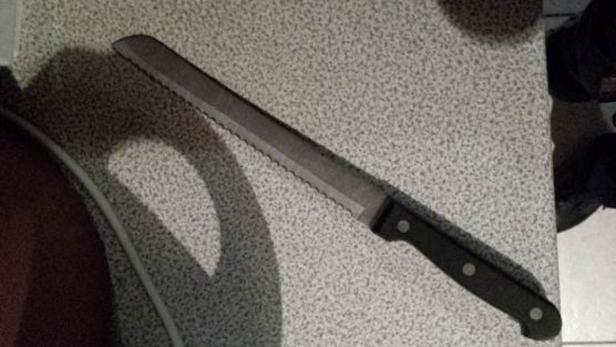 Ein Brotmesser liegt auf einer gesprenkelten Oberfläche.