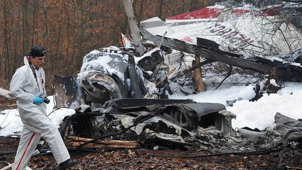 Ein Ermittler in Schutzanzug untersucht die Trümmer eines Flugzeugabsturzes.