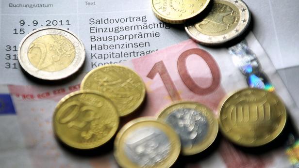 Euro-Münzen und ein Zehn-Euro-Schein liegen auf einem Kontoauszug.