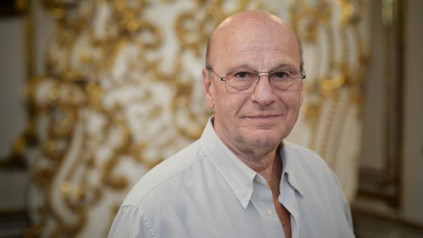 Ein Mann mit Brille und hellem Hemd lächelt in die Kamera.