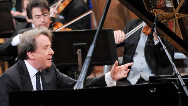 Ein Dirigent leitet ein Orchester am Klavier.