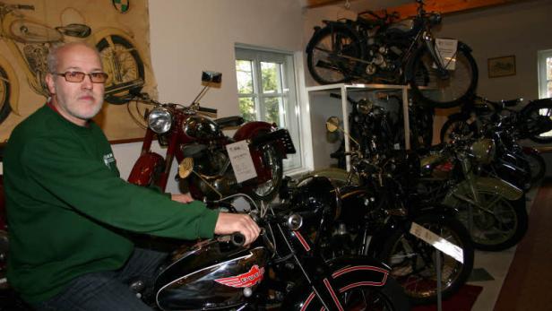 Ein Mann sitzt auf einem Motorrad der Marke Puch in einem Museum.