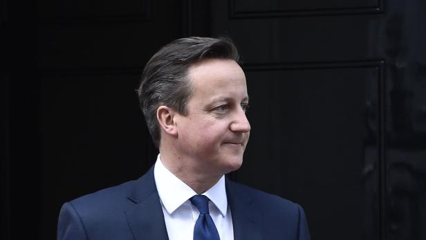 David Cameron vor einer schwarzen Tür.