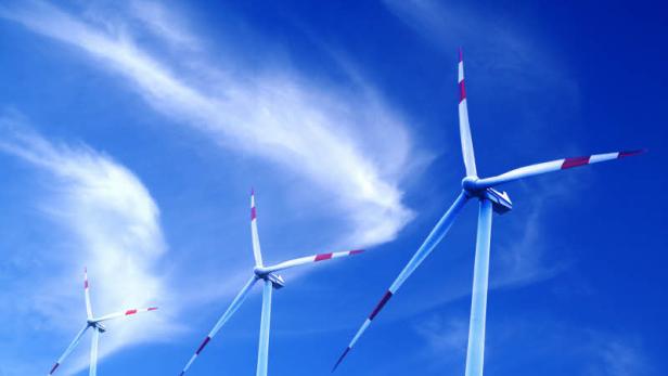 Drei Windräder mit rot-weißen Spitzen vor blauem Himmel.