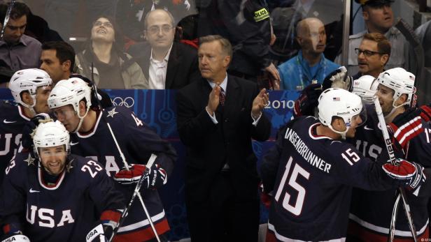 Das US-amerikanische Eishockeyteam jubelt, während der Trainer applaudiert.