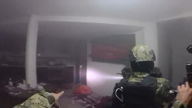 Soldaten betreten mit Waffen und Taschenlampen einen Raum.