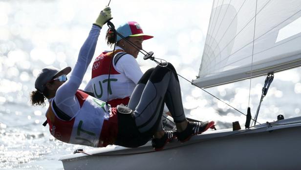 Zwei Seglerinnen steuern ein Segelboot auf dem Wasser.