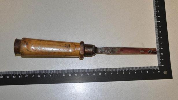 Ein alter Stechbeitel mit Holzgriff liegt neben einem Lineal.