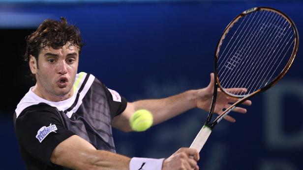 Ein Tennisspieler schlägt einen Ball mit seinem Schläger.