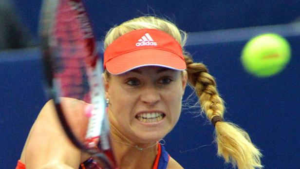 Eine Tennisspielerin mit rotem Visier schlägt einen Ball.