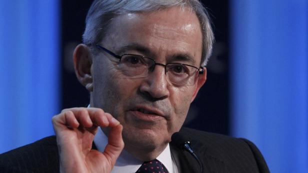 Ein Mann mit Brille gestikuliert vor einem Mikrofon.