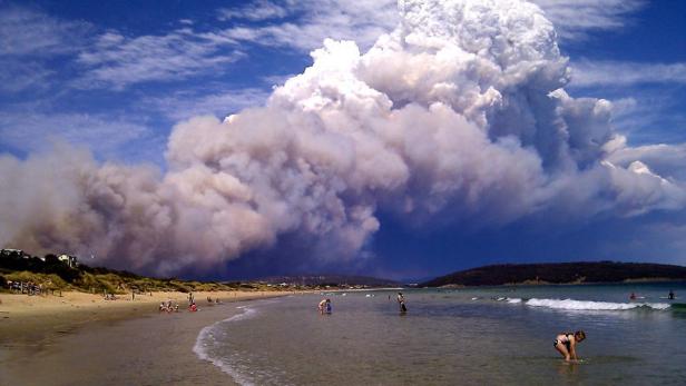 Smoke from a bushfire billows over beach goers at Carlton, about 20 kilometres (12 miles) east of Hobart January 4, 2013. Picture taken January 4, 2013. Bushfires destroyed over 80 homes as temperatures in Australia&#039;s island state Tasmania peaked at record highs on Friday local media reported. REUTERS/Joanne Giuliani (AUSTRALIA - Tags: DISASTER TPX IMAGES OF THE DAY) FOR EDITORIAL USE ONLY. NOT FOR SALE FOR MARKETING OR ADVERTISING CAMPAIGNS. THIS IMAGE HAS BEEN SUPPLIED BY A THIRD PARTY. IT IS DISTRIBUTED, EXACTLY AS RECEIVED BY REUTERS, AS A SERVICE TO CLIENTS