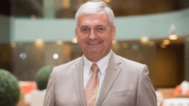 Ein lächelnder Mann in einem hellen Anzug mit Krawatte.