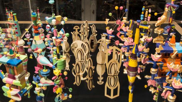 Eine Sammlung von bunten Holzspielzeugen und -figuren auf einer spiegelnden Oberfläche.