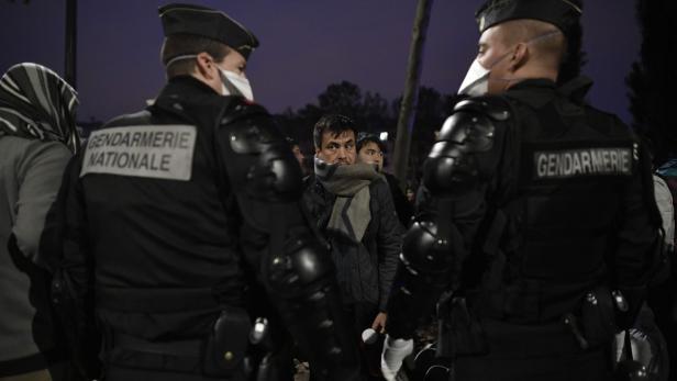 Ein Mann mit Schal steht zwischen zwei Polizisten der Gendarmerie Nationale.