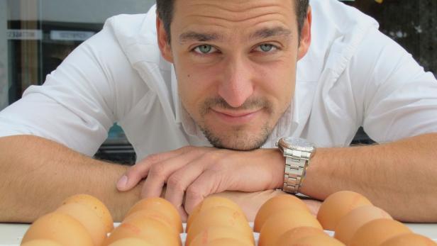 Ein Mann beugt sich über eine Reihe von Eiern.