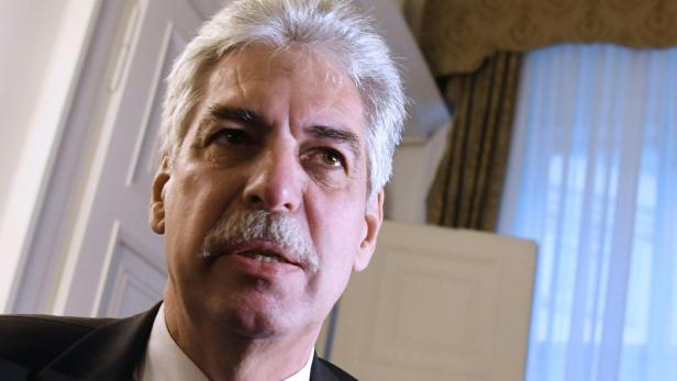 Ein Mann mit grauem Haar und Schnurrbart in einem Anzug.