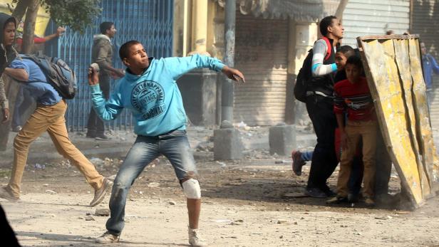 Ein junger Mann wirft einen Stein während einer Auseinandersetzung auf der Straße.