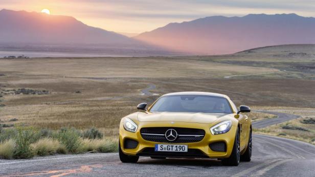 Ein gelber Mercedes-AMG GT steht auf einer Straße vor einer Hügellandschaft im Abendlicht.