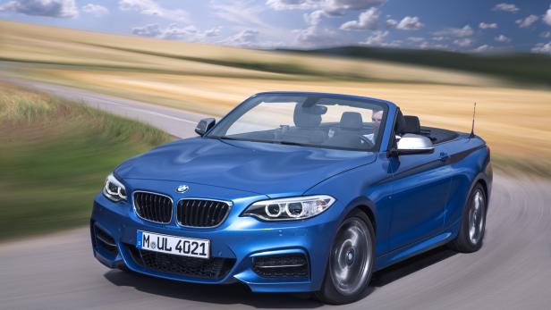 Ein blauer BMW-Cabriolet fährt auf einer Landstraße.