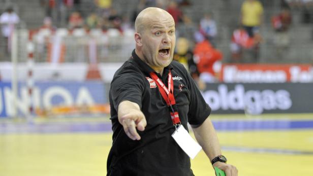 Ein Handballtrainer gestikuliert auf dem Spielfeld und gibt Anweisungen.