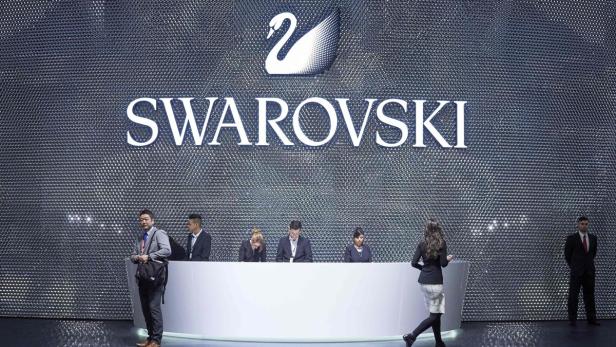 Mitarbeiter sitzen vor dem Swarovski-Logo auf einer Veranstaltung.
