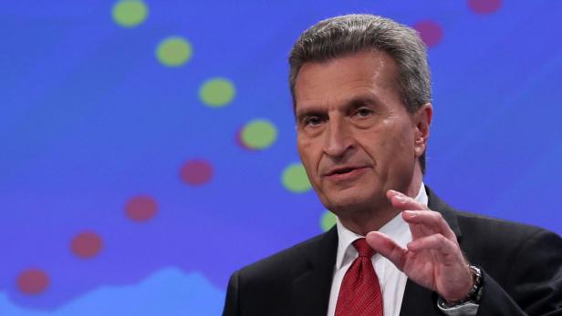 Ein Mann in Anzug und Krawatte gestikuliert vor einem blauen Hintergrund.