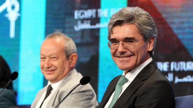 Zwei Männer sitzen lächelnd vor einem Bildschirm mit der Aufschrift „Egypt the Future“.