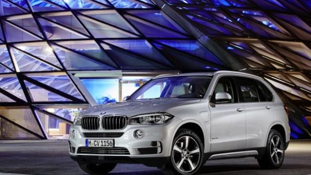Ein silberner BMW X5 vor einem Gebäude mit einer markanten Glasfassade.