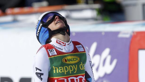 Eine Skirennläuferin blickt mit einem Helm und einer Skibrille nach oben.