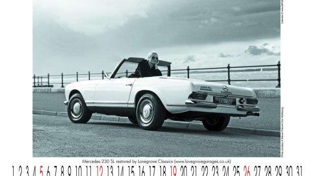 Eine Frau sitzt in einem weißen Mercedes 230 SL Oldtimer am Meer.