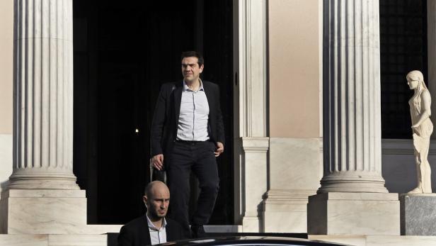 Alexis Tsipras verlässt ein Gebäude, gefolgt von einem Mann im Anzug.