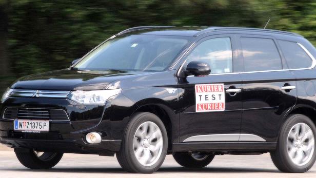 Ein schwarzer Mitsubishi Outlander mit einem „Kurier Test Kurier“-Aufkleber auf der Tür.