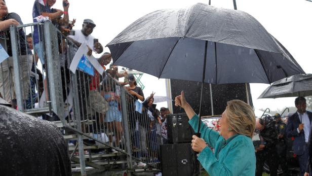 Hillary Clinton gibt bei Regen den Daumen nach oben.