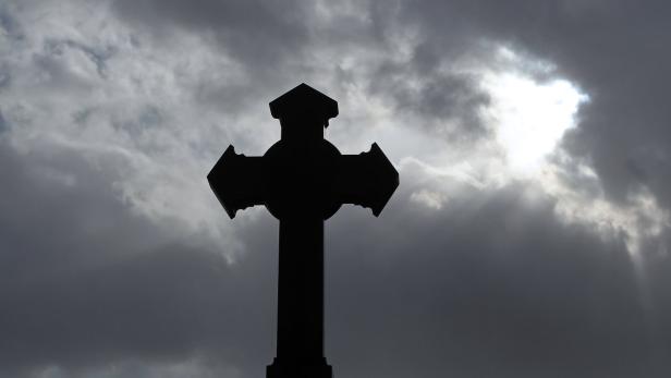 APA2045050 - 15032010 - WIEN - ÖSTERREICH: Ein Kreuz vor dunklen Wolken, aufgenommen am Montag, 15. März 2010, auf einem Wiener Friedhof. APA-FOTO: GEORG HOCHMUTH