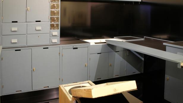Eine Küchenzeile im Bauhausstil mit grauen Schränken und Schubladen.